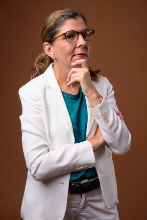 Mature beautiful businesswoman against brown backgroundの写真素材