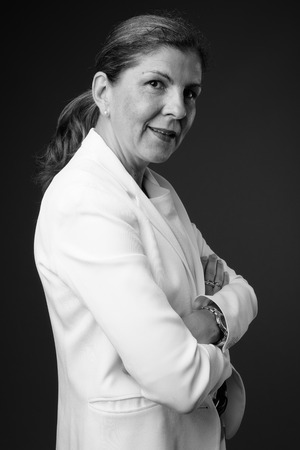 Mature beautiful businesswoman against gray background in blackの写真素材