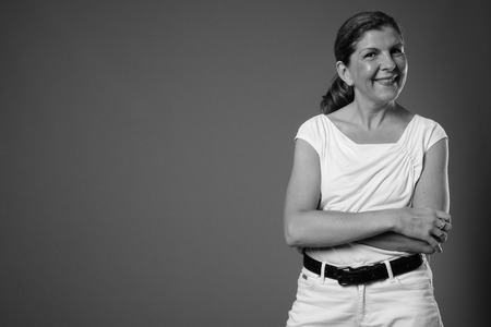 Mature beautiful businesswoman against gray background in blackの写真素材