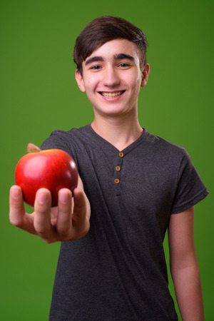 Young handsome Iranian teenage boy against green backgroundの写真素材