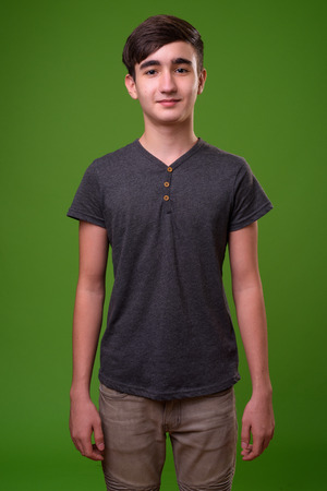 Young handsome Iranian teenage boy against green backgroundの写真素材
