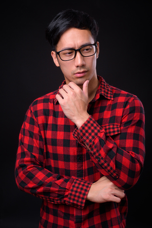 Young handsome Asian man against black backgroundの写真素材