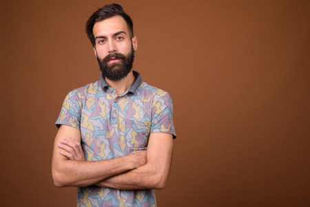 Young handsome bearded Persian man against brown backgroundの写真素材