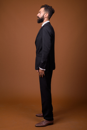 Young handsome bearded Persian businessman against brown backgroの写真素材