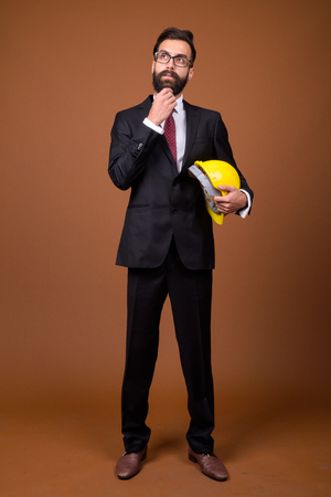 Young handsome bearded Persian businessman against brown backgroの写真素材