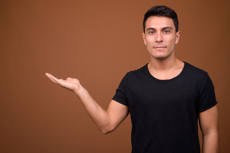 Young handsome Hispanic man against brown backgroundの写真素材