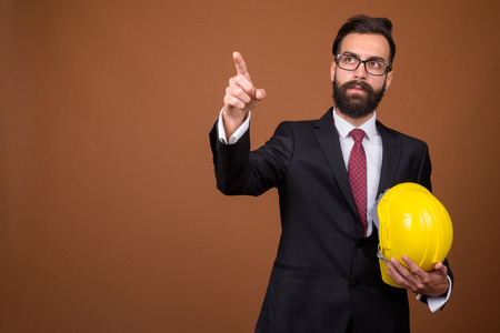 Young handsome bearded Persian businessman against brown backgroの写真素材