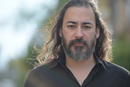 Mature handsome bearded multi-ethnic businessman with long hair in the streets outdoorsの写真素材