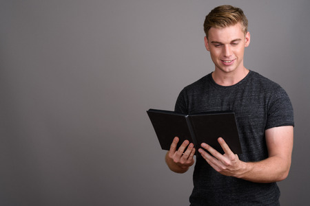 Young handsome man with blond hair wearing gray shirt against grの写真素材
