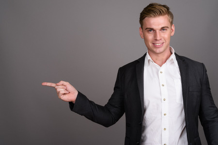 Young handsome businessman with blond hair wearing suit againstの写真素材