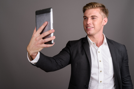 Young handsome businessman with blond hair wearing suit againstの写真素材