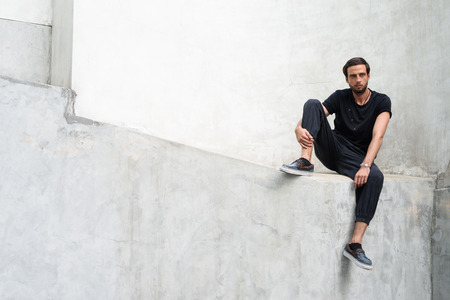 Handsome man against concrete wall in the streets outdoorsの写真素材