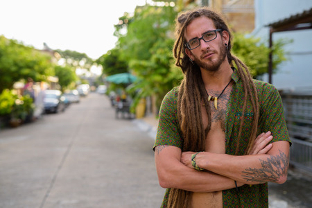 Young handsome Hispanic tourist man with dreadlocks in the stree
