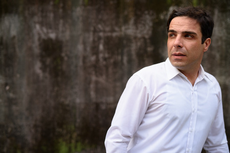 Handsome Persian businessman against concrete wall outdoorsの写真素材