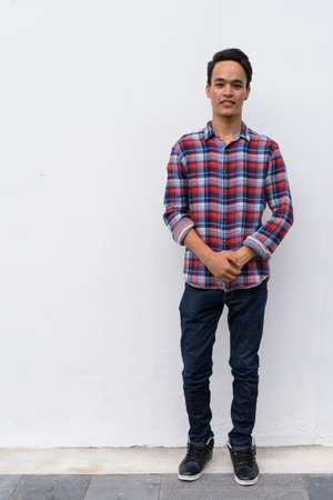 Young handsome Indian man against white wall in the streets outdの写真素材