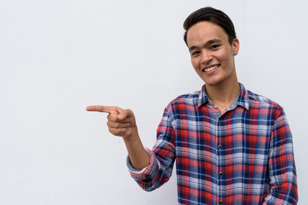 Young handsome Indian man against white wall in the streets outdの写真素材