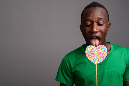 Young African man wearing green shirt against gray backgroundの写真素材