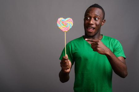 Young African man wearing green shirt against gray backgroundの写真素材