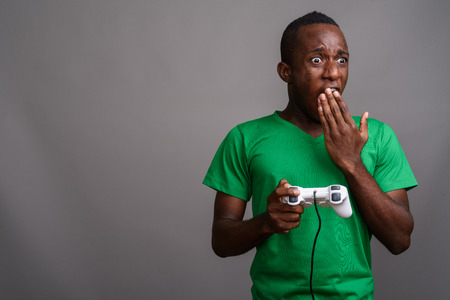 Young African man wearing green shirt against gray backgroundの写真素材