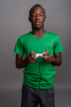 Young African man wearing green shirt against gray backgroundの写真素材