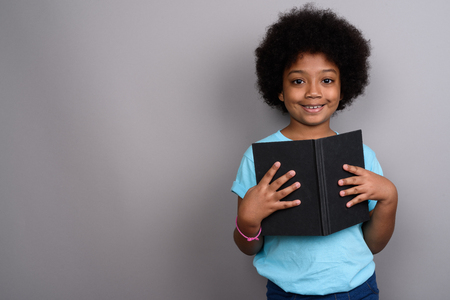 Young cute African girl against gray backgroundの写真素材