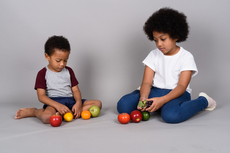 Young cute African siblings together against gray backgroundの写真素材