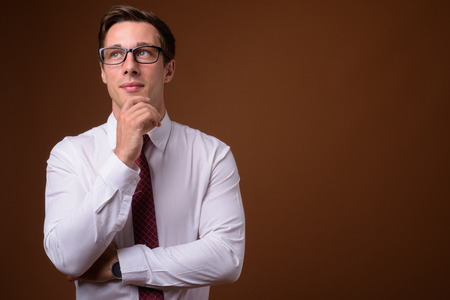 Young handsome businessman wearing eyeglasses against brown backの写真素材