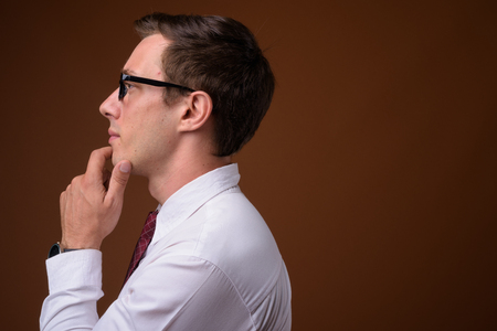 Young handsome businessman wearing eyeglasses against brown backの写真素材