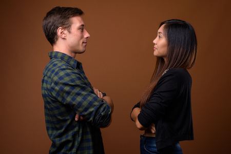 Studio shot of young multi-ethnic couple together against brownの写真素材