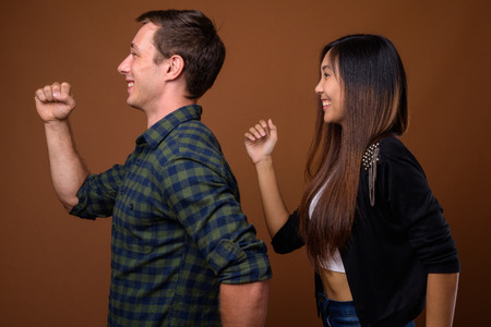 Studio shot of young multi-ethnic couple together against brownの写真素材