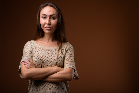 Studio shot of young beautiful woman against brown backgroundの写真素材