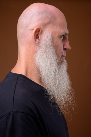 Mature bald man with long gray beard against brown backgroundの写真素材