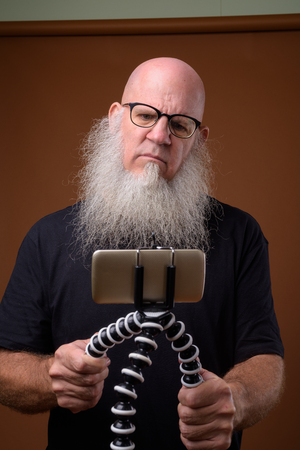 Mature bald man with long gray beard against brown backgroundの写真素材