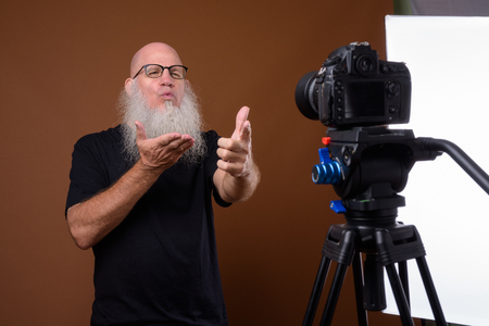 Mature bald man with long gray beard against brown backgroundの写真素材