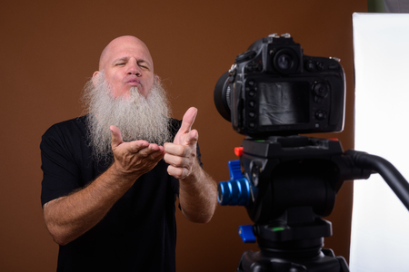 Mature bald man with long gray beard against brown backgroundの写真素材