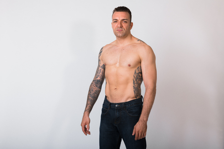 Portrait Of Shirtless Man With Tattoos Against White Backgroundの写真素材