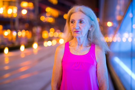 Portrait Of Senior Woman Thinking Outdoors At Nightの写真素材
