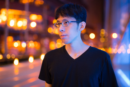 Happy Asian Man Thinking Outdoors At Nightの写真素材