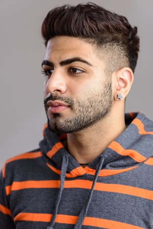 Portrait shot of young handsome Indian man isolated against grayの写真素材