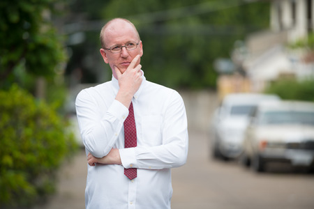 Portrait of mature bald businessman thinking outdoorsの写真素材