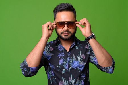 Young bearded Indian man against green background