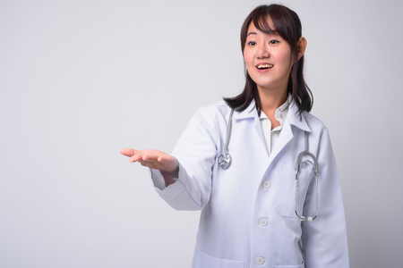 Portrait of beautiful Asian woman doctor against white backgroundの写真素材