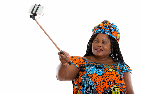Happy fat black African woman smiling while holding selfie stickの写真素材