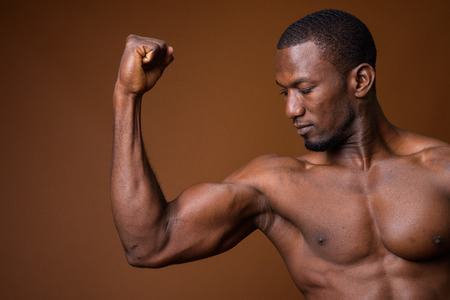 Handsome muscular African man shirtless against brown background