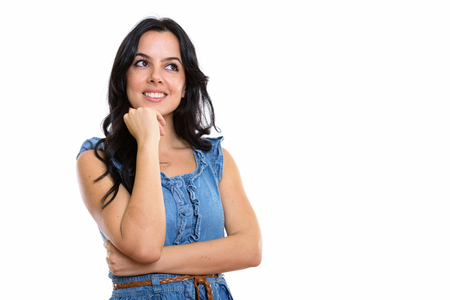 Studio shot of young happy Spanish woman smiling and thinking whの写真素材