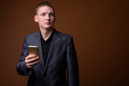 Studio shot of young businessman against brown backgroundの写真素材