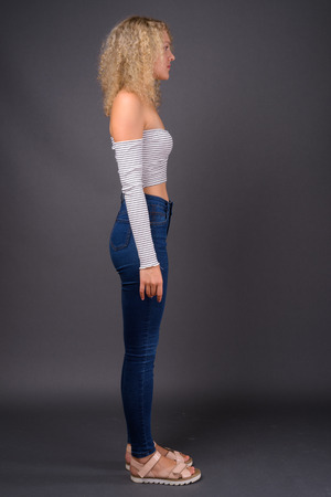 Young beautiful woman with blond curly hair against gray backgroの写真素材