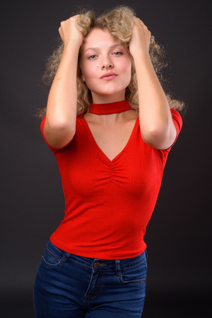 Young beautiful woman with blond curly hair against gray backgroの写真素材