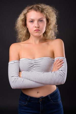Young beautiful woman with blond curly hair against gray backgroの写真素材