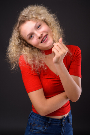 Young beautiful woman with blond curly hair against gray backgroの写真素材